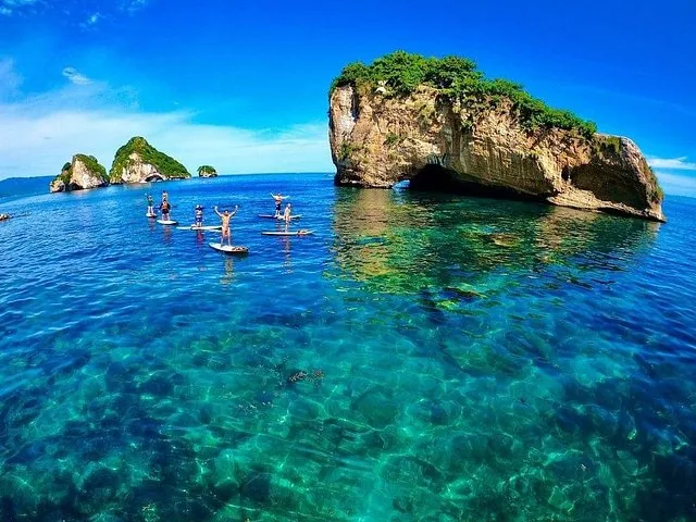 Group of people paddleboarding around Los Arcos rock formations.