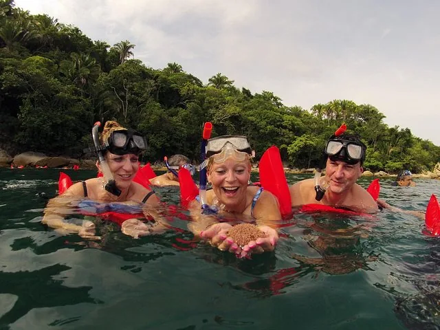 People snorkeling holding a starfish in the water near Los Arcos.